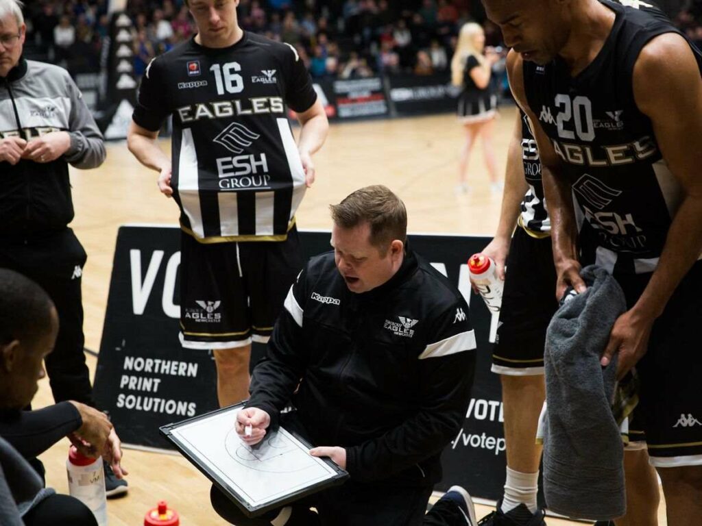 Ian MacLeod drawing a set play in a board showing how is the transition from assistant to head coach